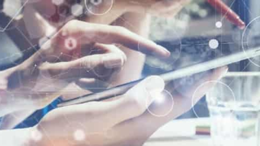 Two people collaborate, using a tablet and stylus at a desk with a glass of water. Overlaid digital graphics suggest technology, data analysis, and innovation.