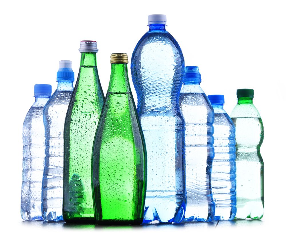 A group of assorted plastic and glass water bottles, some clear and some green, are standing upright together on a reflective surface—much like a well-coordinated labor management consulting team—against a white background.