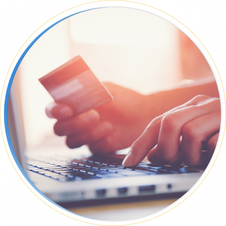 A person holds a credit card in one hand and types on a laptop keyboard with the other, suggesting online shopping or online payment—an ideal scene for Dynamics 365 Commerce users. The image is bright with a warm, sunlit background.