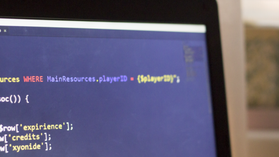 A close-up of a laptop screen displaying code with syntax highlighting in a text editor, set against a softly lit background with curtains and sunlight.