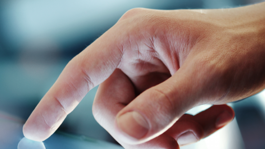 A close-up of a persons hand using their index finger to touch or swipe on a touchscreen device, with a soft focus on the background.