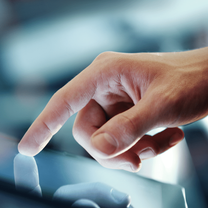 A close-up of a persons hand using their index finger to touch or swipe on a touchscreen device, with a soft focus on the background.