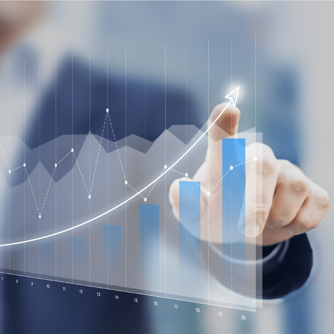 A person in a suit points to a rising bar and line graph on a transparent screen, symbolizing business growth and upward trends.