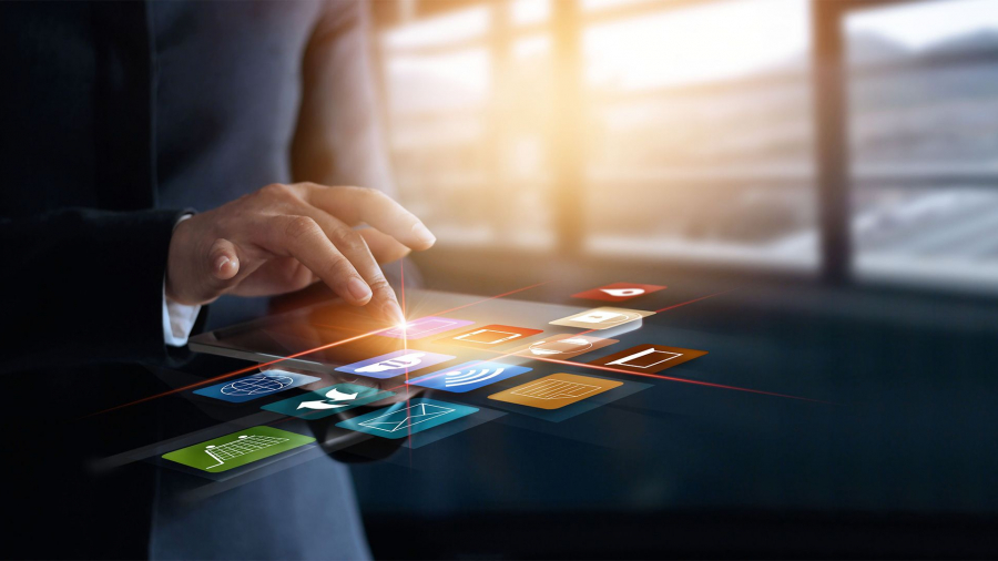 A person in a suit interacts with colorful floating digital icons, representing various apps and technologies like what is omnichannel fulfilment, against a blurred office background with large windows.