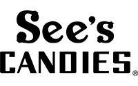Black and white See’s Candies logo with the brand name in stylized lettering on a light background.