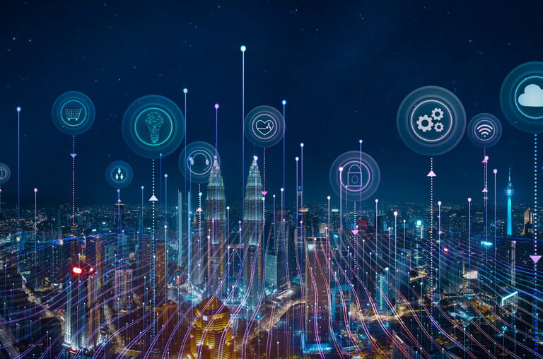 A city skyline at night with digital icons above buildings, representing cloud computing, data, security, and smart technology, connected by glowing lines to illustrate a smart city network.