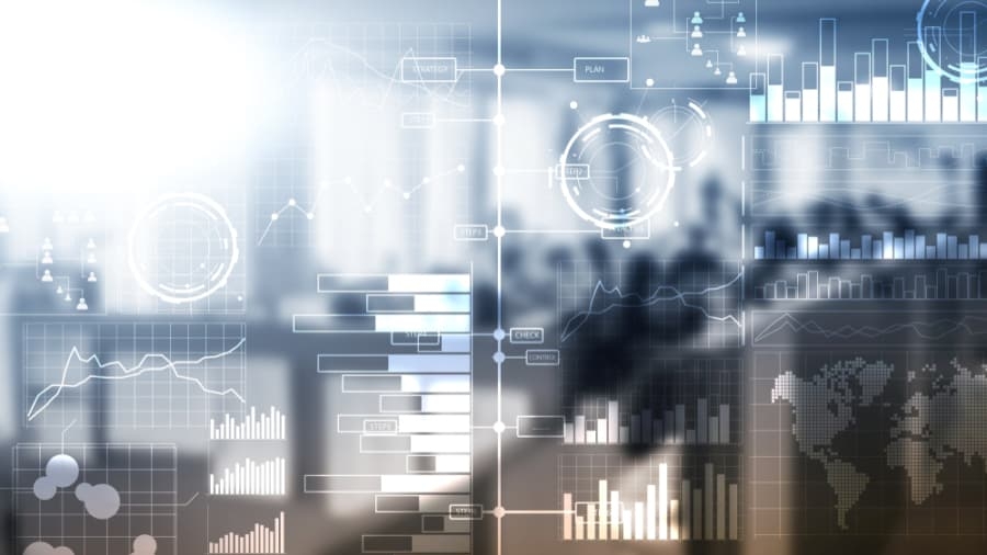 Abstract image of digital business data visualizations, such as bar charts, line graphs, circular diagrams, and a world map—highlighting Impact Analytics—overlaid on a blurred office background with people and desks.
