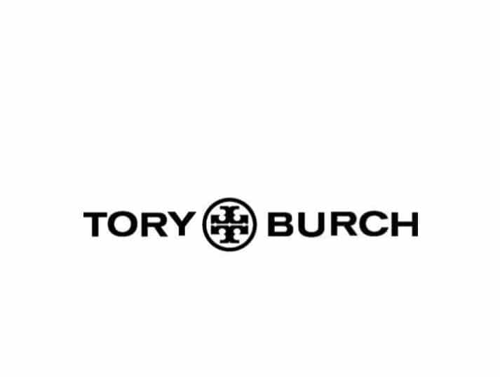 The image shows the Tory Burch logo with bold black text reading TORY BURCH and a decorative circular emblem featuring a symmetrical geometric design between the words. The background is white.