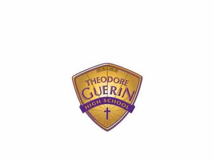 Shield-shaped gold and purple logo for Theodore Guerin High School, featuring the school name and a small cross near the bottom.
