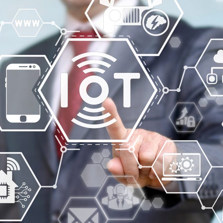 A person in a suit touches a transparent screen displaying hexagonal icons related to IoT (Internet of Things), including symbols for smart devices, cloud, energy, security, and connectivity.