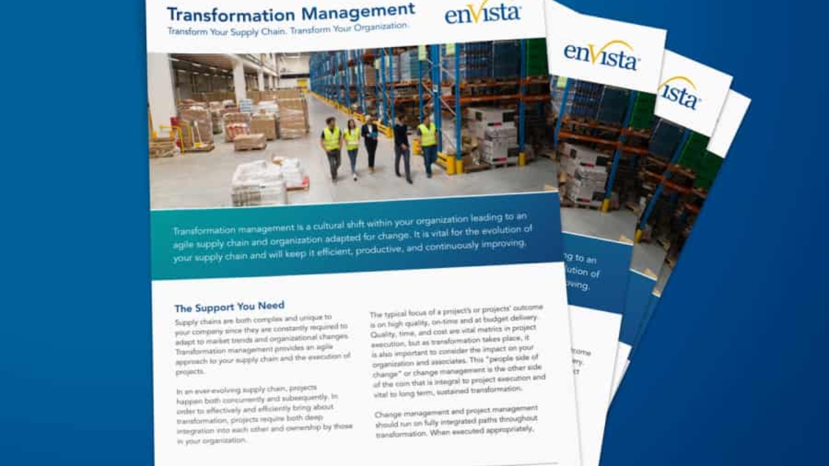 A stack of brochures titled Transformation Management with a photo of five people in safety vests walking in a warehouse, surrounded by shelves and boxes. The brochures feature the enVista logo and text about supply chain transformation.