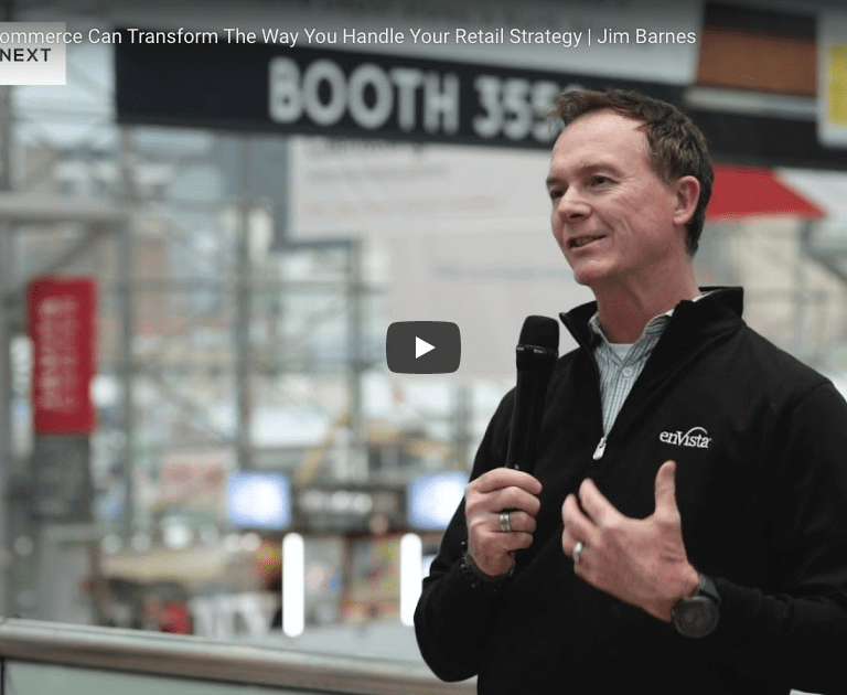 A man in a black jacket speaks into a microphone at an indoor event, with blurred signs and people in the background. The video title is How Unified Commerce Can Transform The Way You Handle Your Retail Strategy | Jim Barnes.