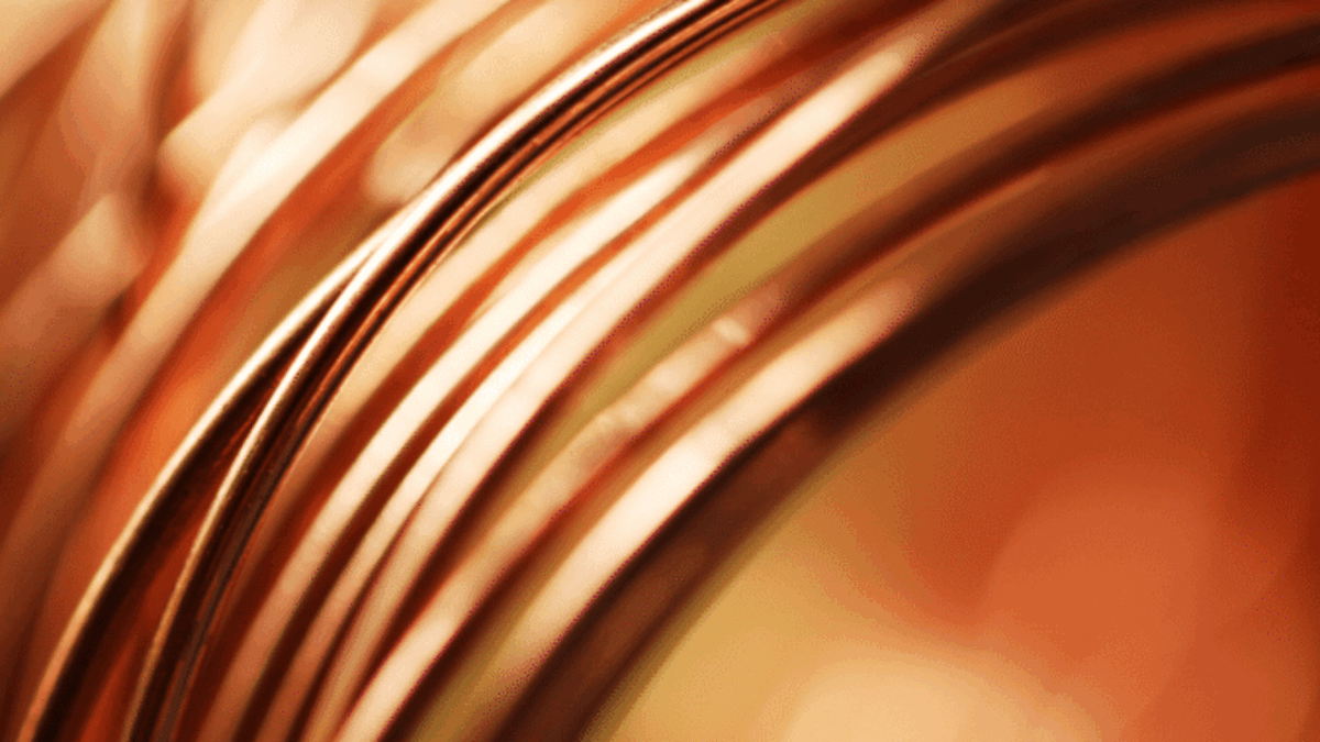 Close-up of several loops of copper wire with a warm, orange glow and soft focus in the background.