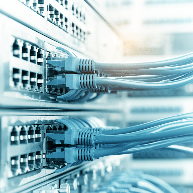 Close-up of several network switches with multiple blue Ethernet cables plugged into the ports, indicating active data connections in a server or data center environment.