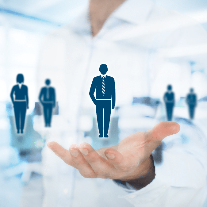 A person holds out their hand with illustrated icons of business professionals, symbolizing talent selection or human resources, against a blurred office background.