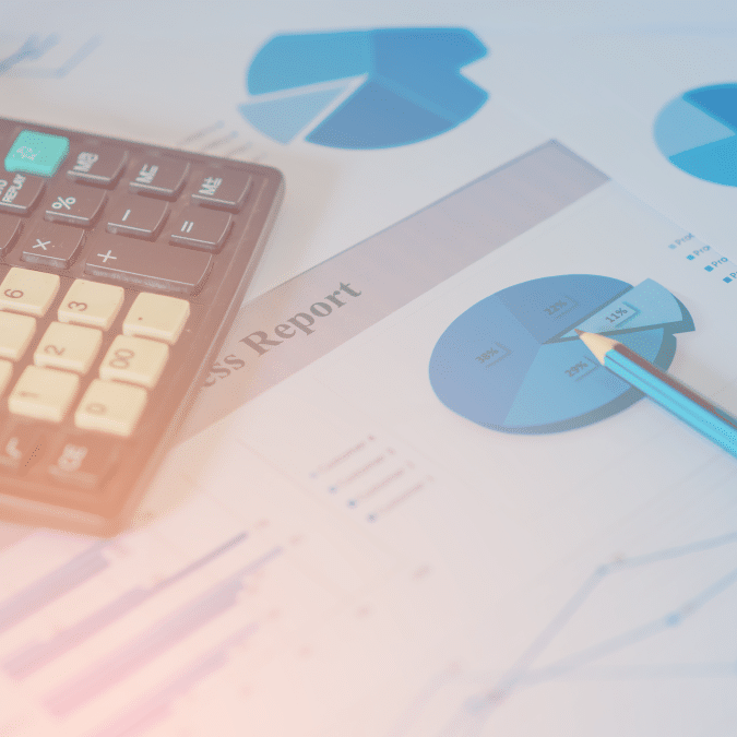 A calculator and a pencil rest on printed business reports featuring pie charts and graphs with financial data.