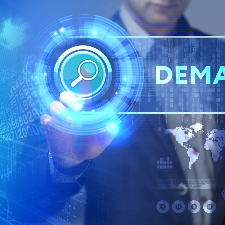 A person in a suit touches a digital search icon on a virtual interface, with the word DEMAND and graphics of data, world maps, and technology in the background.