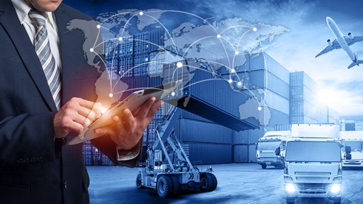 A man in a suit uses a tablet with graphics of a world map and connection lines, overlaid on a background of cargo containers, a forklift, airplanes, and trucks, representing global logistics and supply chain management.