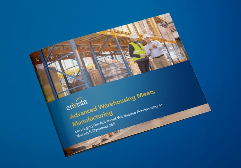 A brochure on a blue surface displays the enVista logo and the title Advanced Warehousing Meets Manufacturing with a photo of two construction workers in safety gear reviewing plans at a building site.