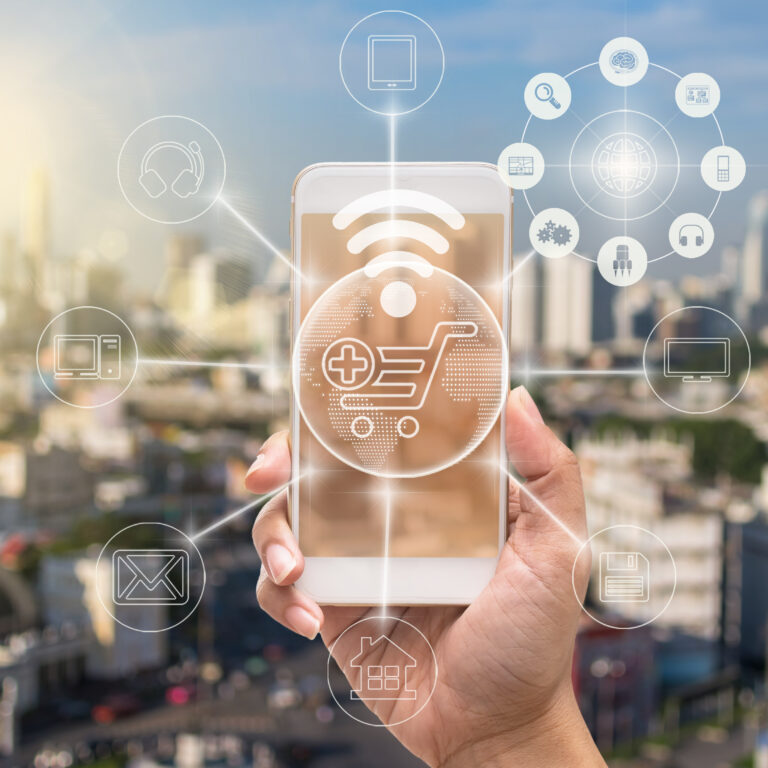 A hand holds a smartphone against a blurred cityscape, displaying a digital shopping cart icon. Translucent icons for order management systems and online services float around the phone, highlighting seamless connectivity.