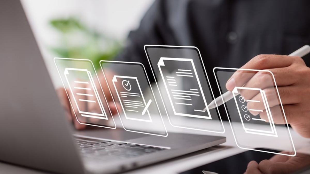 A person using a stylus writes on a digital tablet in front of a laptop, with transparent icons of documents, checklists, and signatures floating in the foreground, symbolizing digital document management.