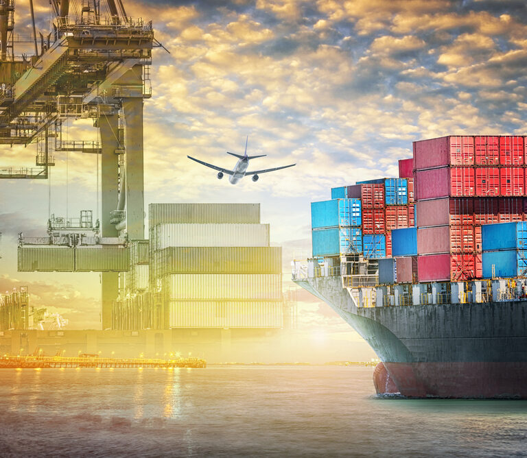 A cargo ship loaded with colorful shipping containers is docked at a port, cranes busy loading and unloading. An airplane flies above, symbolizing global trade and the efficiency of an agile supply chain in modern logistics.