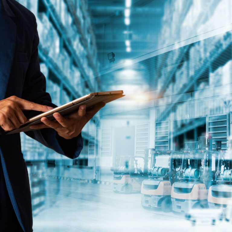 A person in a blue suit uses a tablet, standing in a warehouse with high shelves and rows of forklifts, representing modern inventory management and logistics technology.