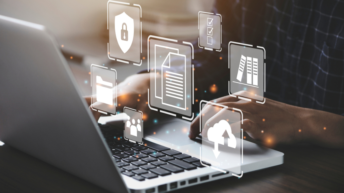 Person typing on a laptop with digital icons for security, documents, cloud storage, folders, and checklists floating above the keyboard, representing Microsoft application management and cybersecurity in digital data environments.