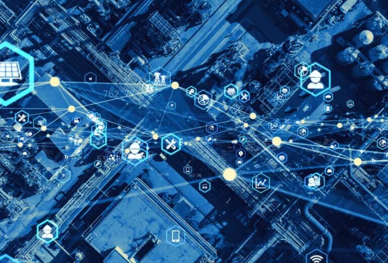 Aerial view of an industrial complex overlaid with digital icons and blue lines representing data connections, illustrating smart technology, the Internet of Things (IoT), and Manufacturing and Operations Strategy Analysis by enVista.