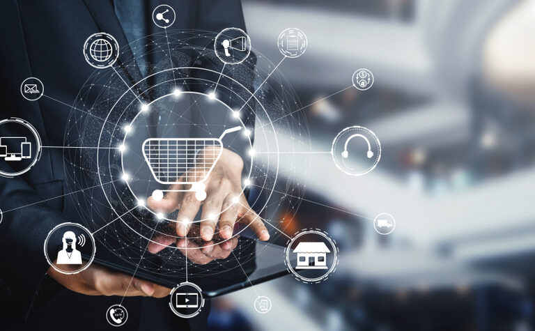 A person in a suit uses a tablet, with digital icons related to online shopping, technology, and communications floating above, symbolizing e-commerce and digital marketing concepts.