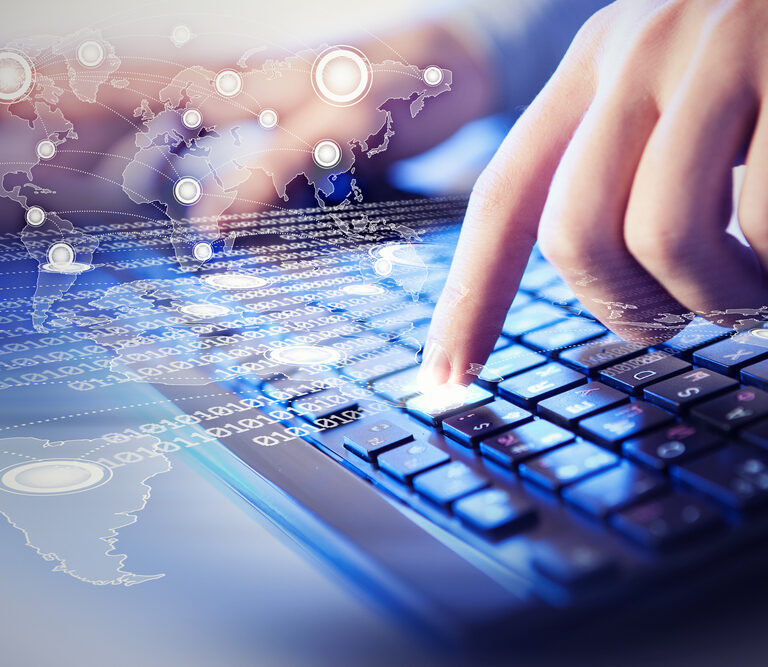 A close-up of fingers typing on a keyboard, with digital graphics of binary code and a world map overlay, symbolizing global communication and technology.