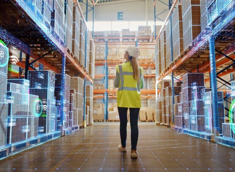 A person in a high-visibility vest and hard hat walks through a warehouse aisle lined with shelves, while digital data and graphs—powered by Microsoft Fabric—are overlaid, depicting smart technology and inventory management.