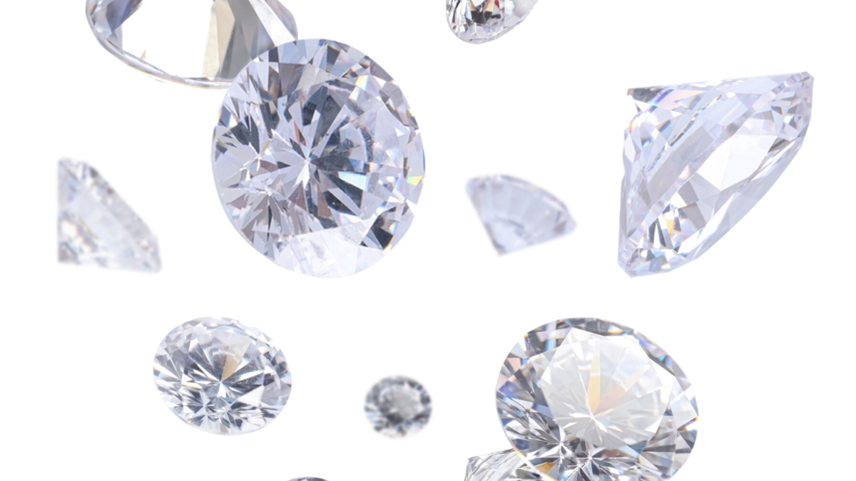 Multiple sparkling, round-cut diamonds of various sizes float against a white background, showcasing their brilliant facets and reflective surfaces.