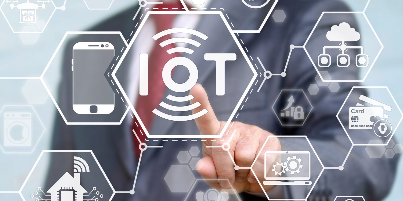 A person in a suit touches a transparent screen displaying hexagonal icons related to IoT (Internet of Things), including symbols for smart devices, cloud, energy, security, and connectivity.