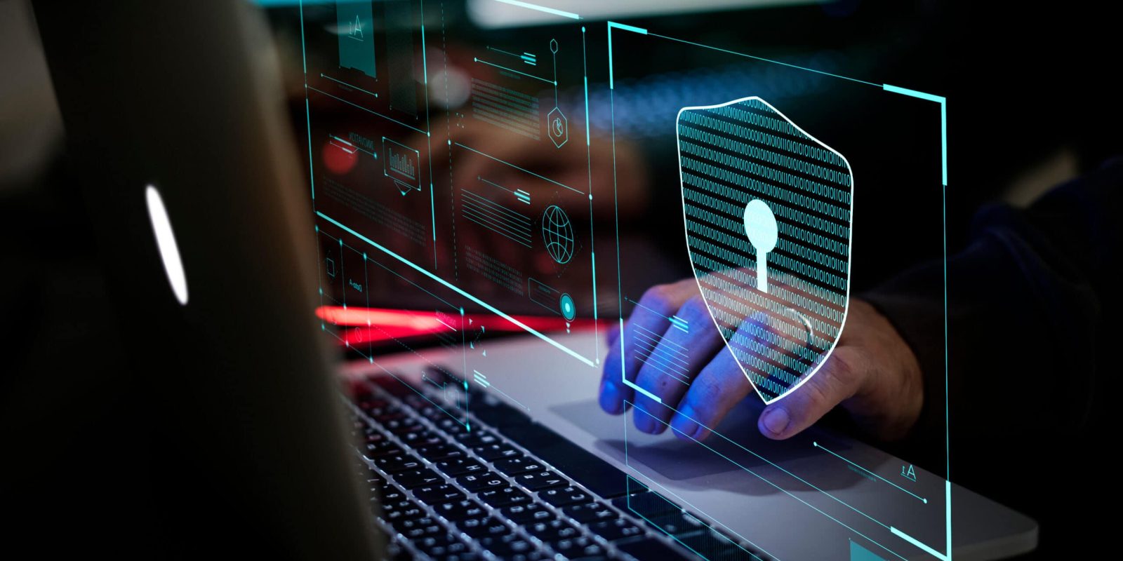 A person types on a laptop with a transparent digital shield and padlock overlay, symbolizing cybersecurity and data protection, highlighting the importance of avoiding the high cost of a security breach. Blurred computer screens and code fill the background.