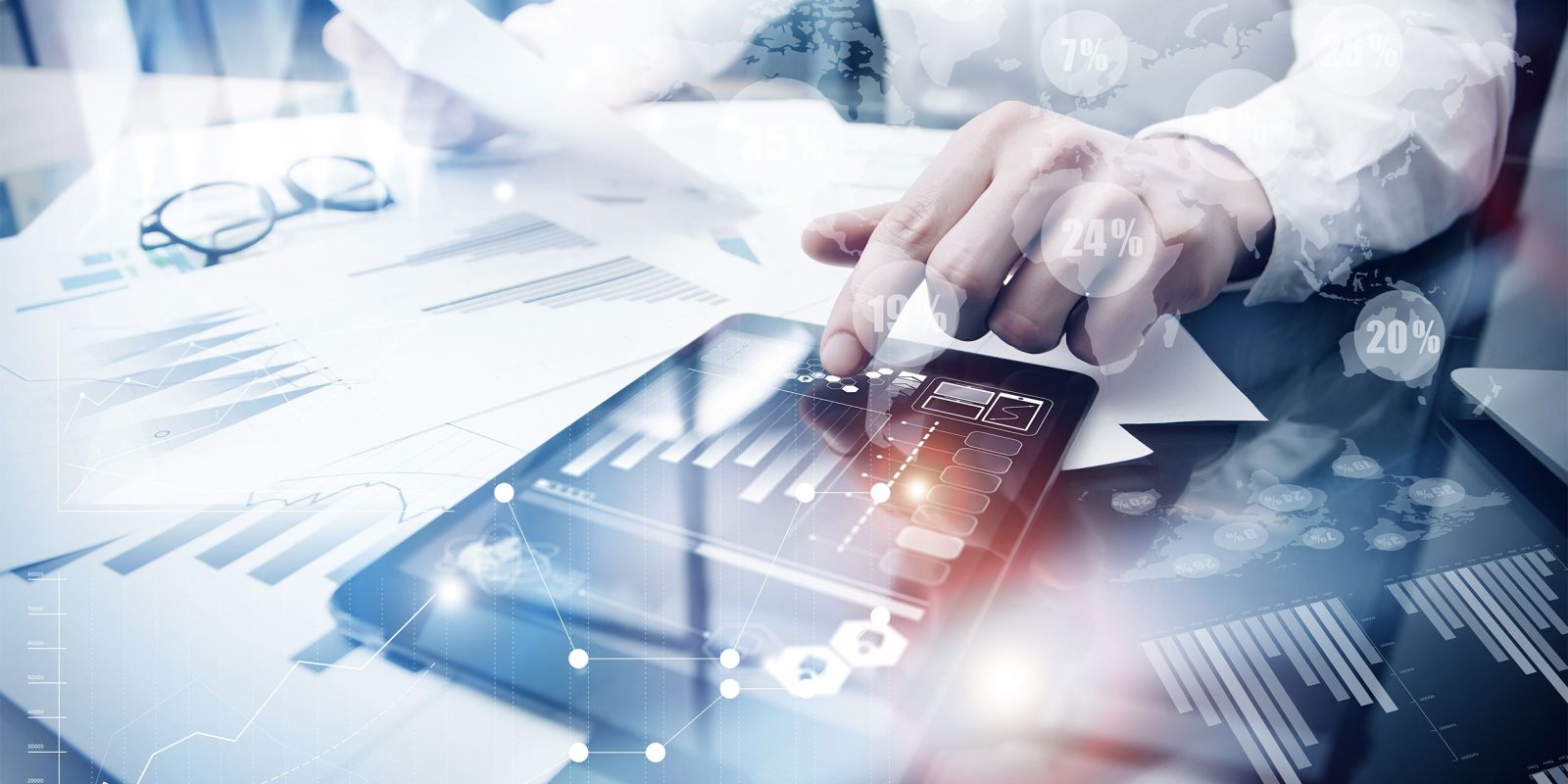 A person reviews financial reports and graphs on paper and a tablet, with data and analytics icons overlaid, suggesting business analysis enhanced by innovative technology solutions.